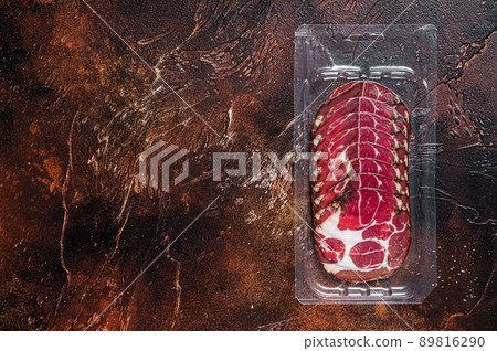 Italian sliced cured coppa meat in vacuum packaging. Dark background. Top view. Copy space Italian sliced cured coppa meat in vacuum packaging. Dark background. Top view. Copy space 89816290