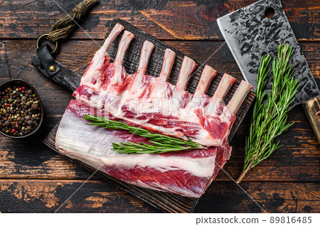 Rack of lamb raw meat with bone on a cutting board. Dark wooden background. Top view Rack of lamb raw meat with bone on a cutting board. Dark wooden background. Top view 89816485
