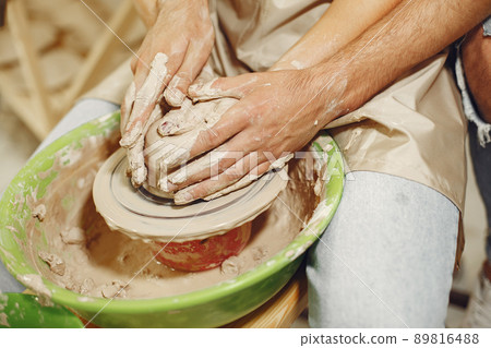 Mutual creative work. Hands creating a bowl on a pottery wheel in a clay studio. Mutual creative work. Hands creating a bowl on a pottery wheel in a clay studio. 89816488