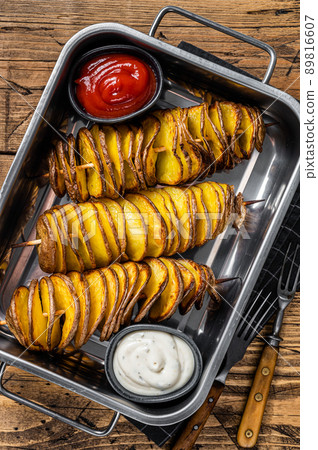 Skewered fried tornado or twist potatoes with ketchup sauce. Wooden background. Top view Skewered fried tornado or twist potatoes with ketchup sauce. Wooden background. Top view 89816607