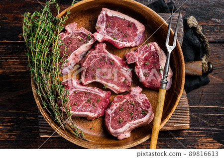 Raw lamb loin rib chops steaks in wooden plate with herbs. Wooden background. Top view Raw lamb loin rib chops steaks in wooden plate with herbs. Wooden background. Top view 89816613