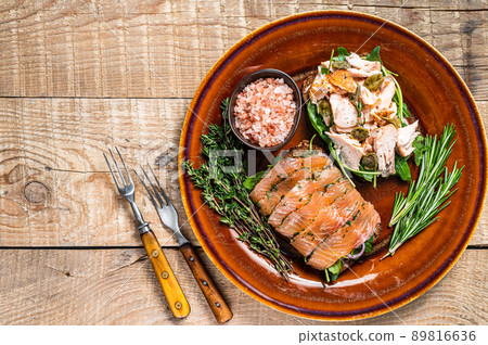 Bruschetta with hot and cold smoked salmon, arugula, capers on a rustic plate with herbs. wooden background. Top view. Copy space Bruschetta with hot and cold smoked salmon, arugula, capers on a rustic plate with herbs. wooden background. Top view. Copy space 89816636