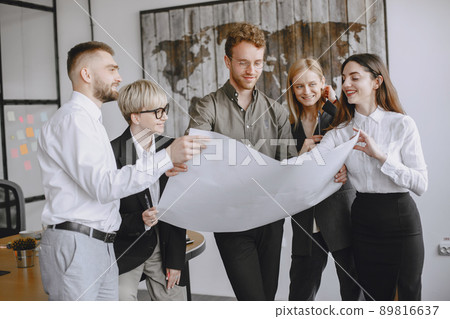 People are working on the project. Men and women in suits sitting at the table. Businesspeople looking at blueprints. People are working on the project. Men and women in suits sitting at the table. Businesspeople looking at blueprints. 89816637