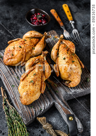Whole Grilled quails on a wooden cutting board. Black background. Top view Whole Grilled quails on a wooden cutting board. Black background. Top view 89816738