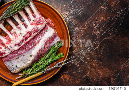 Raw fresh rack of lamb with green herbs. Dark background. Top view. Copy space Raw fresh rack of lamb with green herbs. Dark background. Top view. Copy space 89816740