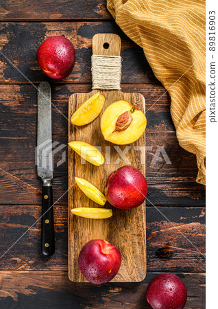 Sliced ripe red nectarines on a chopping Board. Dark Wooden background. Top view 89816903