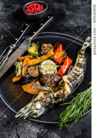 Baked whole icefish with grilled vegetables. Black background. Top view Baked whole icefish with grilled vegetables. Black background. Top view 89816908