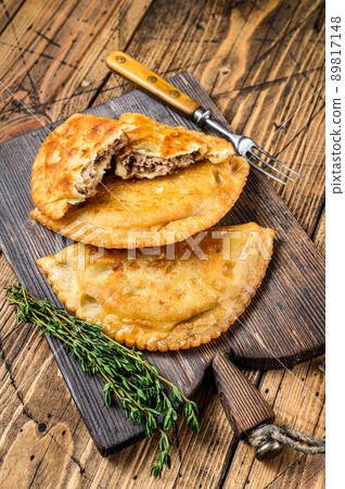 Chilean fried empanadas filled with minced beef meat served on a wooden cutting board. Wooden background. Top view 89817148