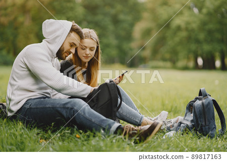 Tourists in a summer forest. Girl in a black t-shirt. Man use a phone. Tourists in a summer forest. Girl in a black t-shirt. Man use a phone. 89817163