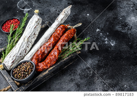 Spanish dry cured sausages salami, fuet and chorizo in a wooden tray. Black background. Top view. Copy space 89817183