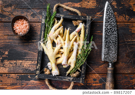 Raw Chicken paws feets on butcher chopping board with knife. Dark wooden background. Top view Raw Chicken paws feets on butcher chopping board with knife. Dark wooden background. Top view 89817207