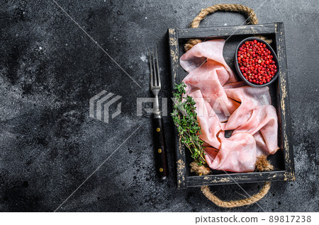 Thin sliced Smoked pork ham in wooden tray. Black background. Top view. Copy space Thin sliced Smoked pork ham in wooden tray. Black background. Top view. Copy space 89817238