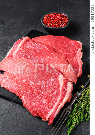 Raw beef meat round steak on a marble board. Black background. Top view Raw beef meat round steak on a marble board. Black background. Top view 89817328