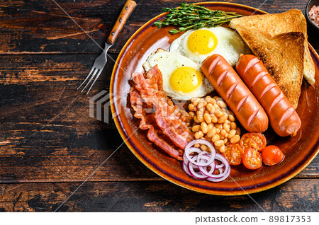 Traditional Full English breakfastt with fried eggs, sausages, bacon, beans and toasts. Dark wooden background. top view. Copy space Traditional Full English breakfastt with fried eggs, sausages, bacon, beans and toasts. Dark wooden background. top view. Copy space 89817353