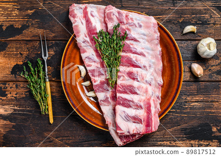 Raw pork loin spare ribs with thyme. Dark wooden background. Top view 89817512