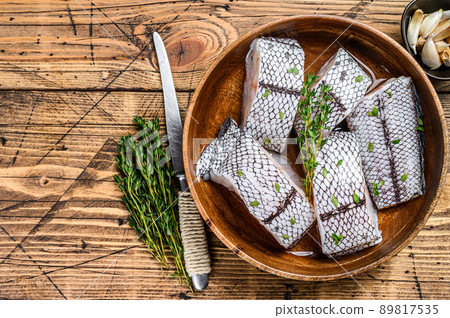 Cut Raw grenadier macrurus white fish without head in a wooden plate. Wooden background. Top view. Copy space 89817535