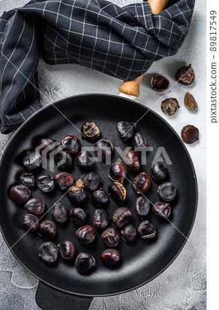 Roast chestnuts in a pan on a wooden table. White background. Top view Roast chestnuts in a pan on a wooden table. White background. Top view 89817549