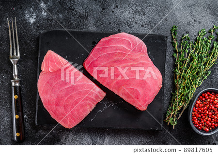 Raw tuna steak on a marble cutting Board . Black background. Top view 89817605