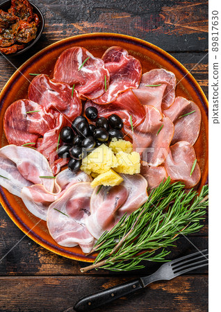 Italian meat platter with prosciutto ham, bresaola, pancetta, salami and parmesan. Dark wooden background. Top view 89817630