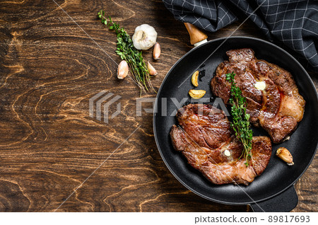 Grilled marble meat steaks Chuck eye roll in a pan. Dark wooden background. Top view. Copy space Grilled marble meat steaks Chuck eye roll in a pan. Dark wooden background. Top view. Copy space 89817693