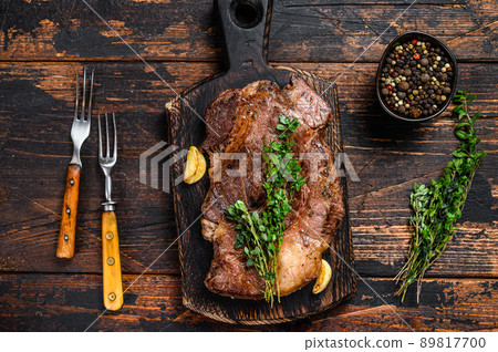 Grilled Chuck eye roll beef meat steak on a cutting board. Dark wooden background. Top view 89817700