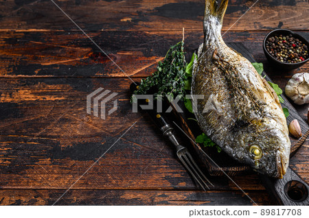 Grilled Dorada sea bream fish on a cutting board. Dark wooden background. Top view. Copy space Grilled Dorada sea bream fish on a cutting board. Dark wooden background. Top view. Copy space 89817708