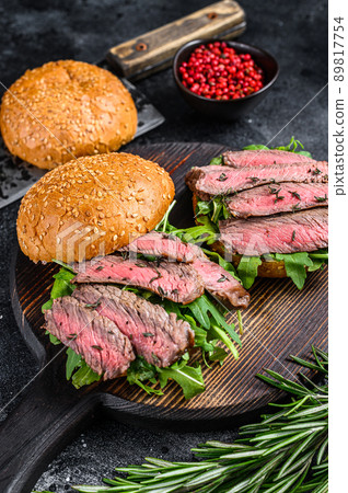 Traditional sliced cold cuts roast beef burger with onion, gherkin, arugula and spinach. Black background. Top view 89817754