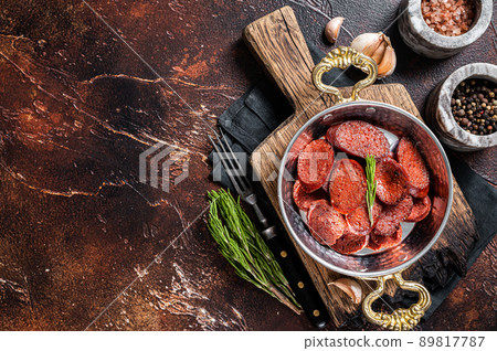 Turkish fried sausage sucuk in a pan. Dark background. Top view. Copy space Turkish fried sausage sucuk in a pan. Dark background. Top view. Copy space 89817787