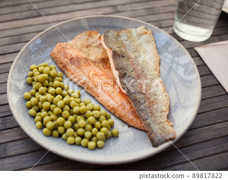 Top view of baked trout fillet served on plate with peas closeup Top view of baked trout fillet served on plate with peas closeup 89817822