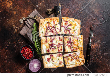 French tarte flambee with cream cheese, bacon and onions. Flammkuchen from Alsace region. Dark background. Top view 89817862