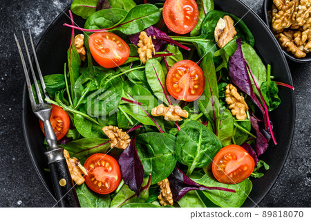Vegetarian salad with mix leaves mangold, swiss chard, spinach, arugula and nuts in a salad bowl. Black background. Top view Vegetarian salad with mix leaves mangold, swiss chard, spinach, arugula and nuts in a salad bowl. Black background. Top view 89818070