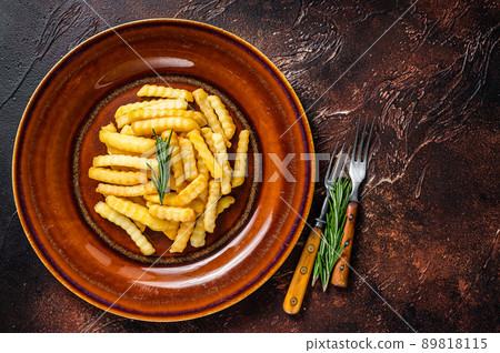 Fried Crinkle French fries potatoes or chips in a rustic plate. Dark background. Top view. Copy space Fried Crinkle French fries potatoes or chips in a rustic plate. Dark background. Top view. Copy space 89818115