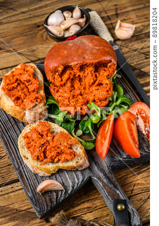 Tapaa sandwichs with Sobrassada cured pork meat sausage and tomato on a wooden cutting board. wooden background. Top view Tapaa sandwichs with Sobrassada cured pork meat sausage and tomato on a wooden cutting board. wooden background. Top view 89818204