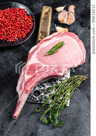 Raw tomahawk pork chop meat steak on a meat cleaver. Black background. Top view 89818212