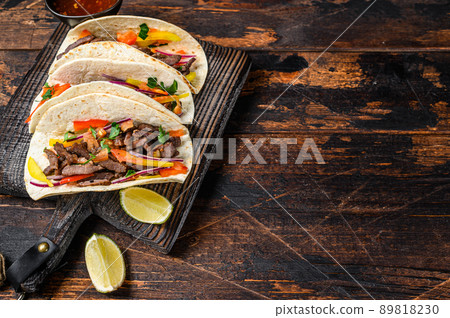 Tacos shells with pork meat, onion, tomato, sweet pepper and salsa. Mexican food. Dark wooden background. Top view. Copy space Tacos shells with pork meat, onion, tomato, sweet pepper and salsa. Mexican food. Dark wooden background. Top view. Copy space 89818230