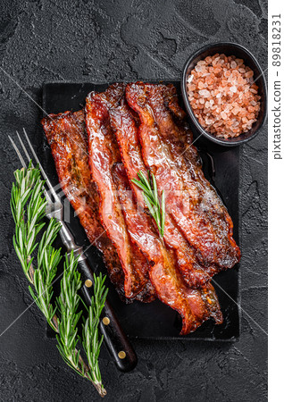 Fried crunchy Streaky Bacon stripes. Black background. Top view Fried crunchy Streaky Bacon stripes. Black background. Top view 89818231