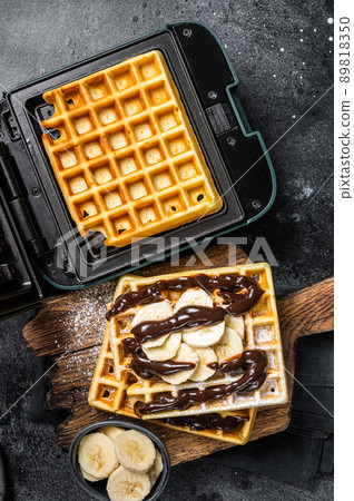 Breakfast with Belgian waffles, banana and Chocolate Syrup. Black background. Top view 89818350