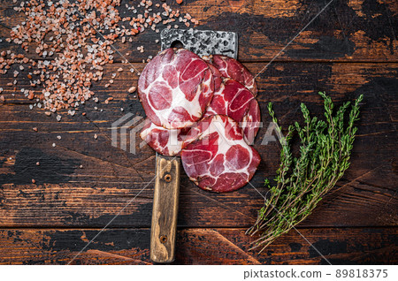 Coppa, Capocollo, Capicollo Cured ham on meat cleaver. Dark wooden background. Top view Coppa, Capocollo, Capicollo Cured ham on meat cleaver. Dark wooden background. Top view 89818375