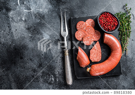 Turkish Sliced Sucuk meat sausage on a marble board with thyme. Black background. Top view. Copy space 89818380