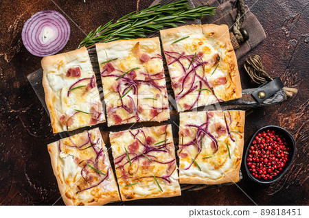 French tarte flambee with cream cheese, bacon and onions. Flammkuchen from Alsace region. Dark background. Top view 89818451