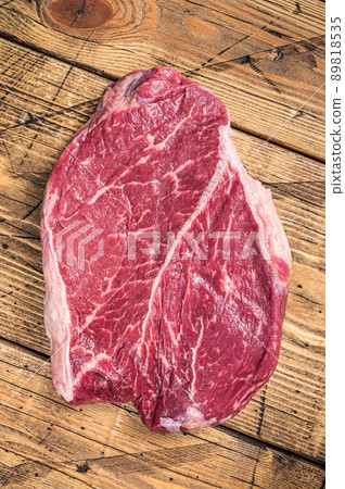 Dry aged raw beef round steak cut on a butcher table. wooden background. Top view 89818535