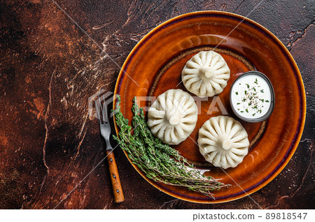 Khinkali Dumplings with beef and lamb meat on rustic plate with herbs. Dark background. Top view. Copy space 89818547