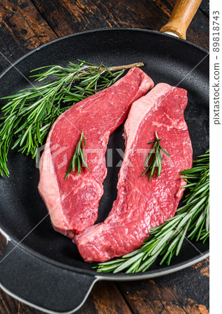 Raw beef meat rump steak in a pan. Dark wooden background. Top view 89818743