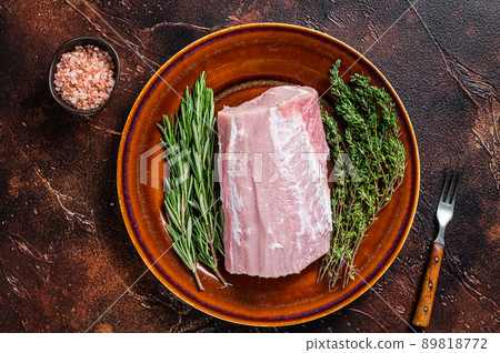 Fresh Raw pork loin meat with thyme and rosemary on rustic plate. Dark background. Top view 89818772