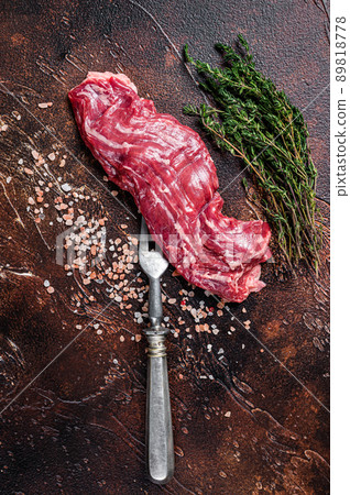 Raw machete skirt beef steak on meat fork. Dark background. Top view 89818778
