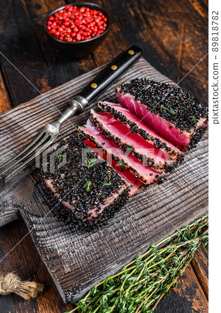 Homemade Cut Grilled Sesame Tuna steak on a cutting board. Dark Wooden background. Top view Homemade Cut Grilled Sesame Tuna steak on a cutting board. Dark Wooden background. Top view 89818782