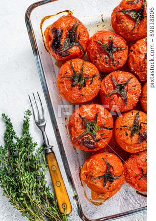 Roasted tomatoes with olive oil and thyme in baking dish. White background. Top view Roasted tomatoes with olive oil and thyme in baking dish. White background. Top view 89818806
