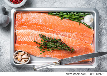 Raw uncooked sea salmon fillet fish in a kitchen tray with herbs. White background. Top view 89818973
