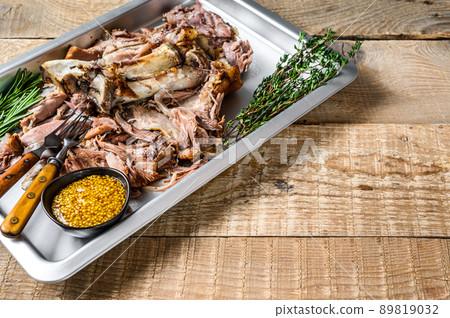 Roast pork knuckle eisbein meat on a baking pan with herbs. Wooden background. Top view. Copy space 89819032