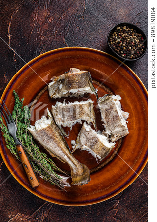 Baked cod white fish in a plate. Dark wooden background. Top view Baked cod white fish in a plate. Dark wooden background. Top view 89819084